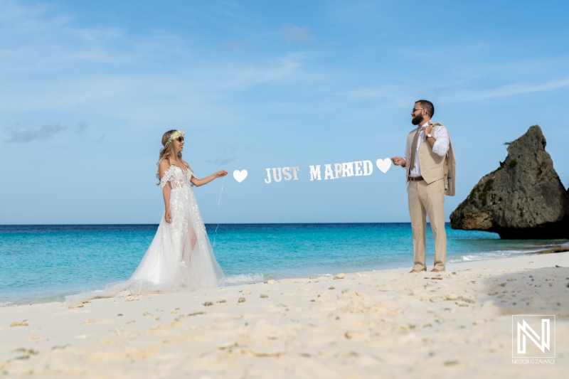 A Newlywed Couple Celebrates Their Marriage on a Serene Beach, Holding a Sign That Reads Just Married Against a Backdrop of Clear Blue Skies and Gentle Waves