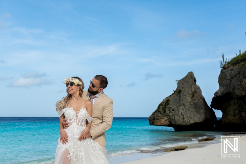 A Couple Embraces on a Beautiful Beach in Bermuda, Surrounded by Clear Blue Water and Intriguing Rock Formations, Celebrating Their Wedding Day With Joy and Love