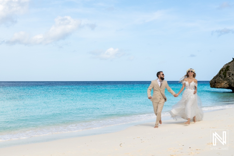 Couple Joyfully Running Along a Serene Beach in Wedding Attire, With Turquoise Waters and Gentle Waves on a Sunny Day