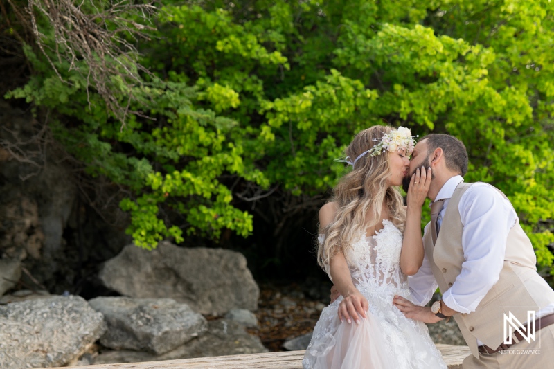 Beach Wedding Couple Sharing a Kiss Surrounded by Lush Greenery During a Sunny Day, Capturing a Moment of Love and Joy in Nature\'s Beauty