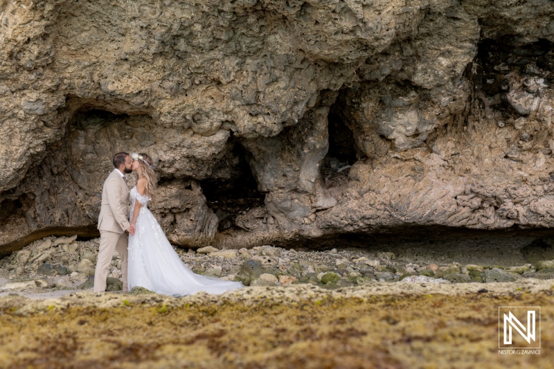 A Newlywed Couple Shares a Romantic Kiss on the Beach, Surrounded by Rugged Cliffs and Natural Beauty During Sunset