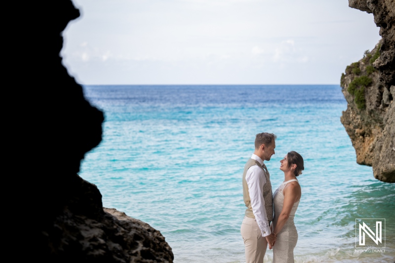 Couple stands together during trash the dress session at Cas Abao Beach in Curacao on a sunny day