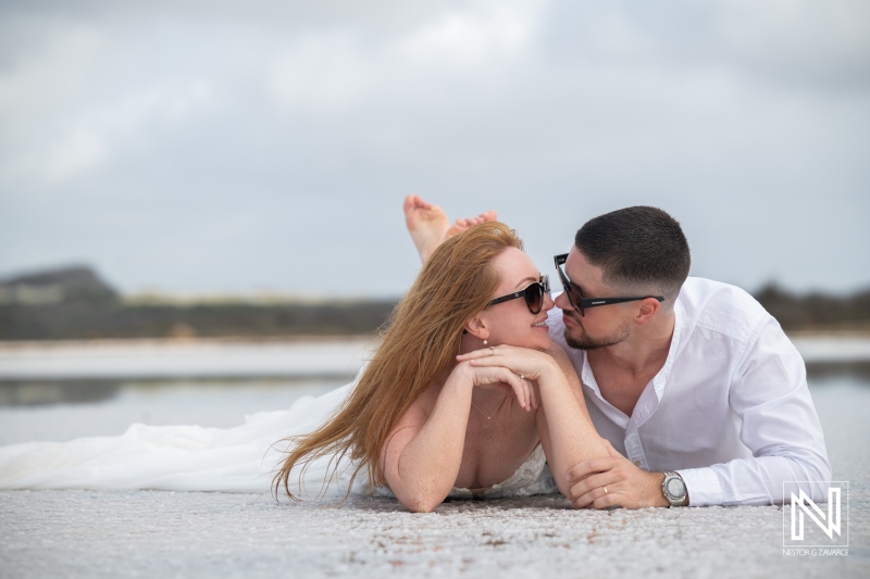 Couple enjoys trash the dress session in Curacao with sandy beach and romantic gesture