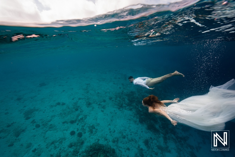 Couples swim underwater during trash the dress session in Curacao