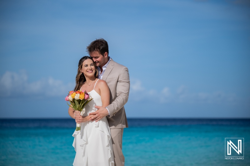Couple enjoys trash the dress session at Cas Abao Beach in Curacao with vibrant flowers and ocean view