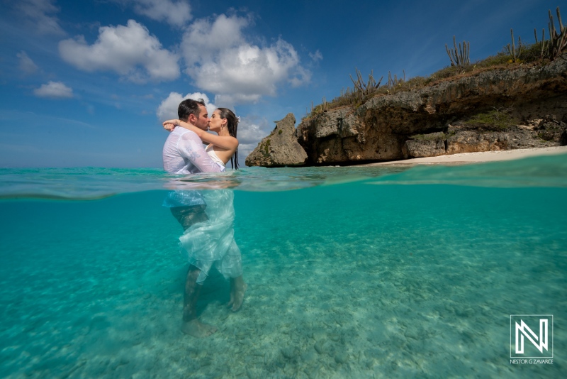 Trash the dress session at Cas Abao Beach in Curacao captures couple in ocean water against rocky backdrop