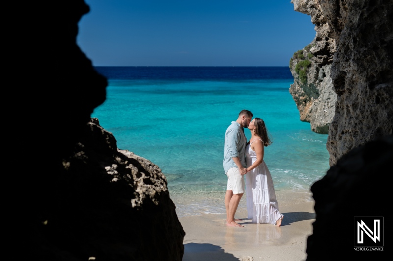 Couple shares an intimate moment while trashing the dress at Cas Abao Beach in Curacao with stunning blue waters and rocky backdrop