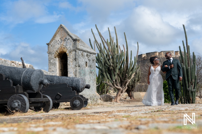 Newly Married Couple Strolls Hand in Hand Past Historic Cannons and Stunning Cactus Landscape at a Fortress in Daylight