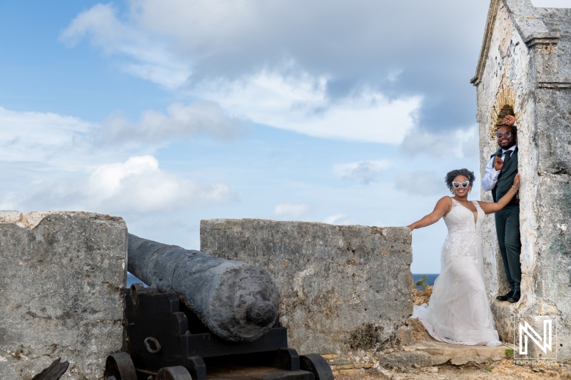 A Romantic Wedding Couple Poses at a Historic Fort With a Cannon, Enjoying a Sunny Day by the Ocean During Their Outdoor Ceremony