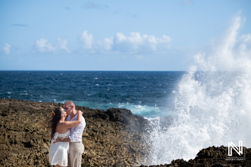 Couple embraces during a trash the dress session at Shete Boka National Park in Curacao with waves crashing behind them