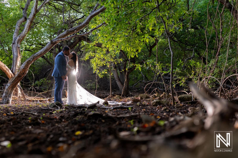 Couple shares an intimate moment in Curacao during a trash the dress session amid lush greenery and soft natural light