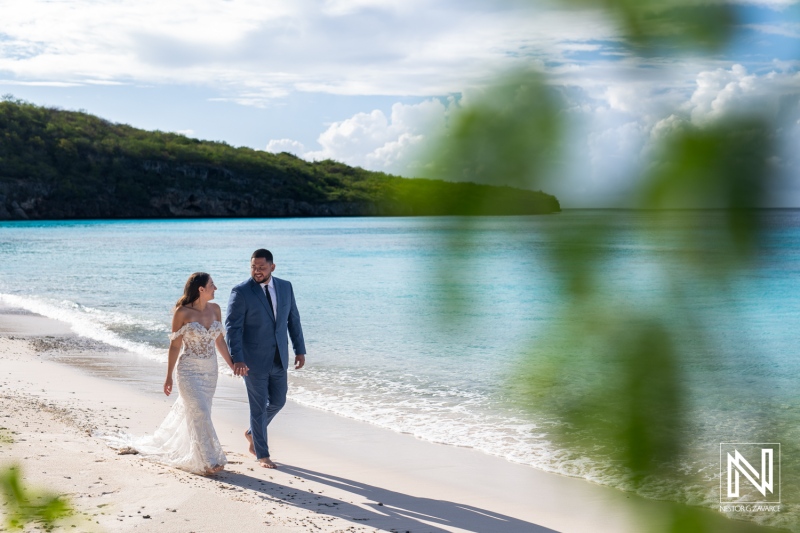 Couple enjoys a romantic stroll along the beach in Curacao during a Trash the Dress session, capturing unforgettable memories by the crystal-clear water