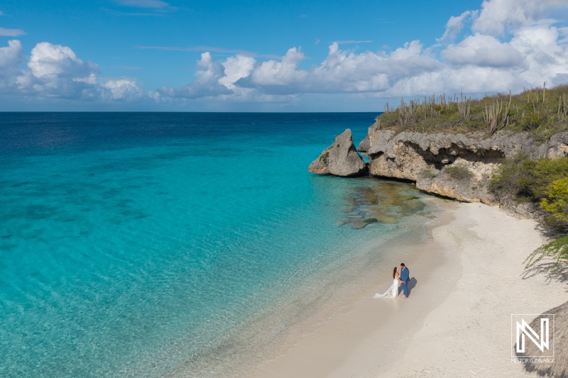 Couple celebrating their love in Curacao during a Trash the Dress session on a stunning beach with turquoise waters and dramatic cliffs