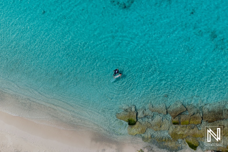 Couple enjoys a romantic trash the dress session in Curacao's turquoise waters at sunset