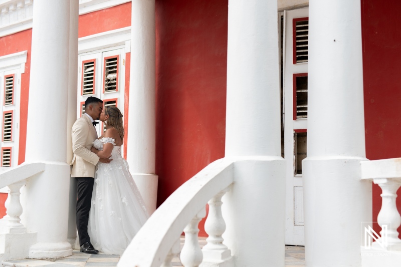 Couple enjoying a romantic trash the dress session in Curacao with vibrant background and elegant attire