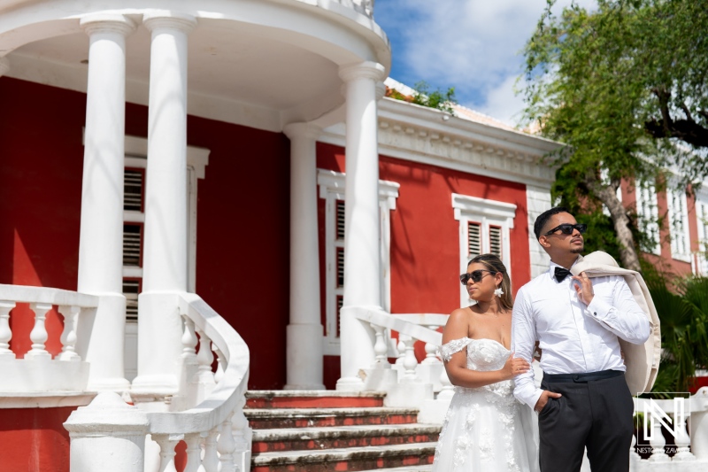 Elegant couple in wedding attire enjoying a Trash the Dress session in Curacao under bright sunshine by historic architecture
