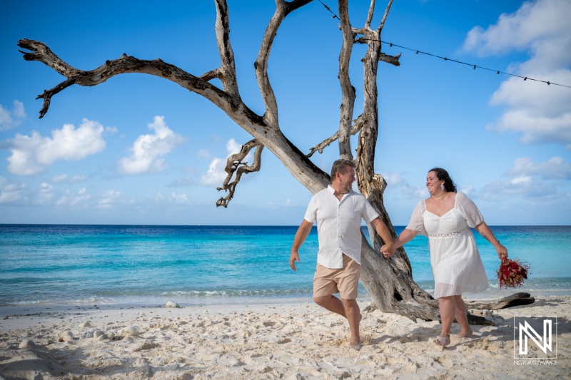 Couple walks along the beach during trash the dress photoshoot at Cas Abao Beach in Curacao under a bright sky