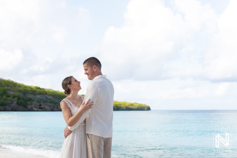 Couple Enjoying a Romantic Moment on a Beach During Golden Hour, With Soft Waves and Lush Greenery in the Background Overlooking the Tranquil Sea