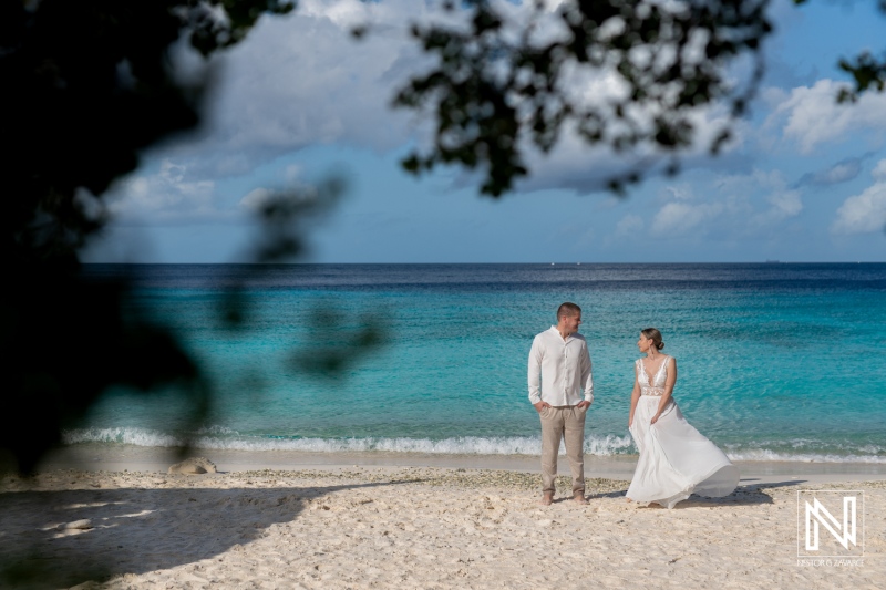 A Couple Shares a Romantic Moment on a Serene Beach During Their Wedding Celebration at Sunset, With Gentle Waves and Soft Clouds in the Background