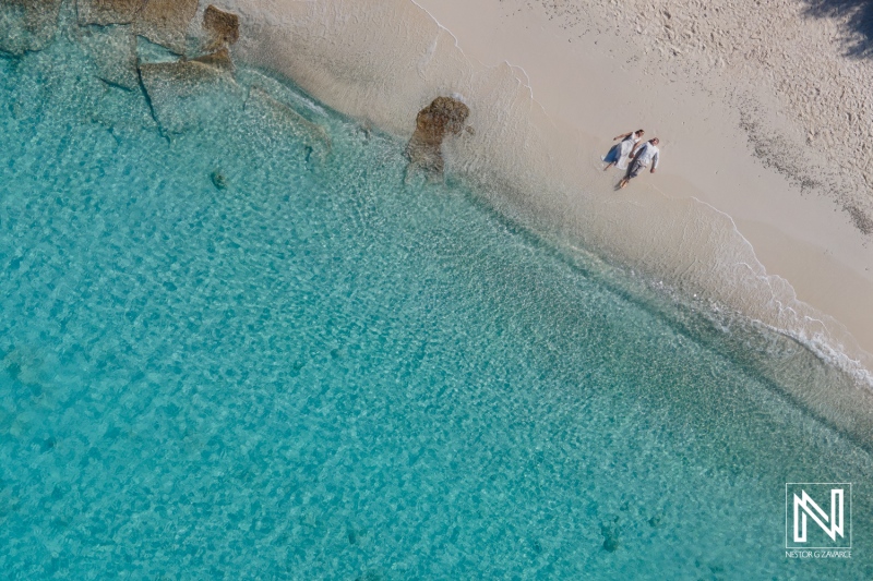 Aerial View of Three Friends Walking Along a Pristine Beach With Clear Turquoise Water on a Sunny Day Near a Tropical Island in the Summer