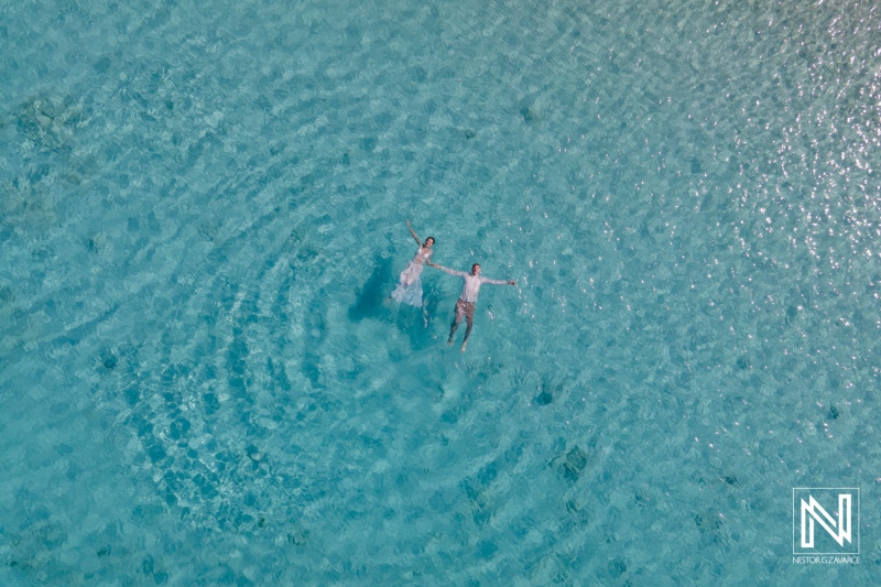 Couple Floating Peacefully in a Clear Turquoise Lagoon Under Bright Sunlight, Enjoying a Serene Day of Relaxation and Connection in a Tropical Paradise