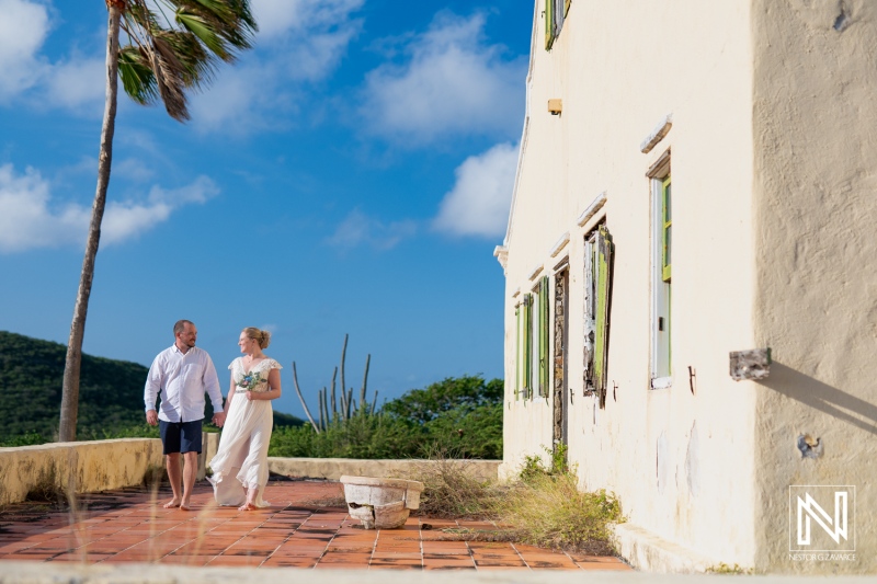 Couple enjoys a romantic stroll at Cas Abao Beach during their Trash the Dress session in Curacao under a clear blue sky