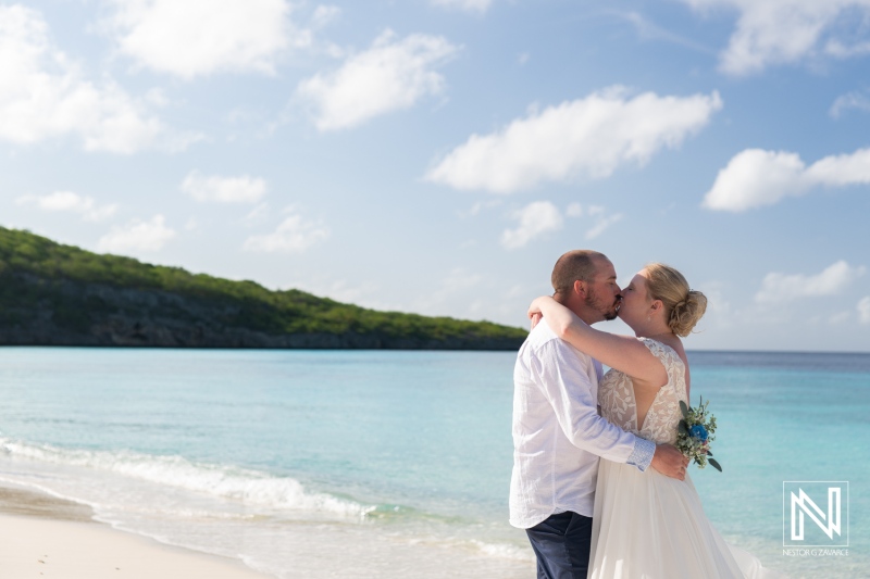Couple shares a romantic kiss during a Trash the Dress session at Cas Abao Beach in Curacao under a clear sky
