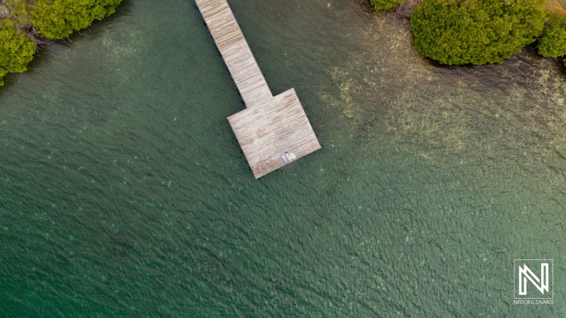 Experience a unique trash the dress moment at the tranquil dock in Curacao surrounded by serene waters and lush greenery