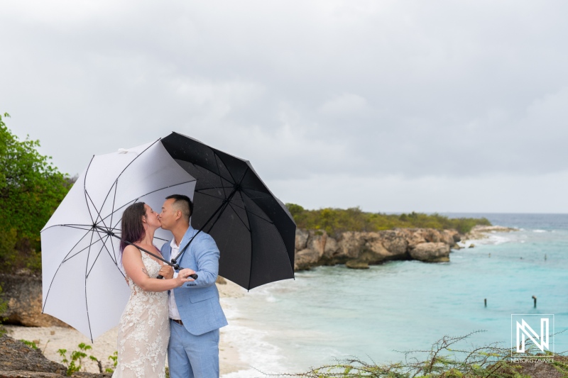 Couple shares a romantic kiss under umbrellas in Curacao during a colorful Trash the Dress session by the beach