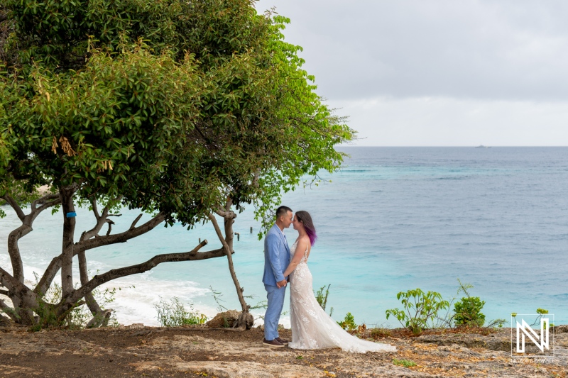Couple embraces in wedding attire during a trash the dress session by the stunning beach in Curacao, showcasing love amid beautiful nature