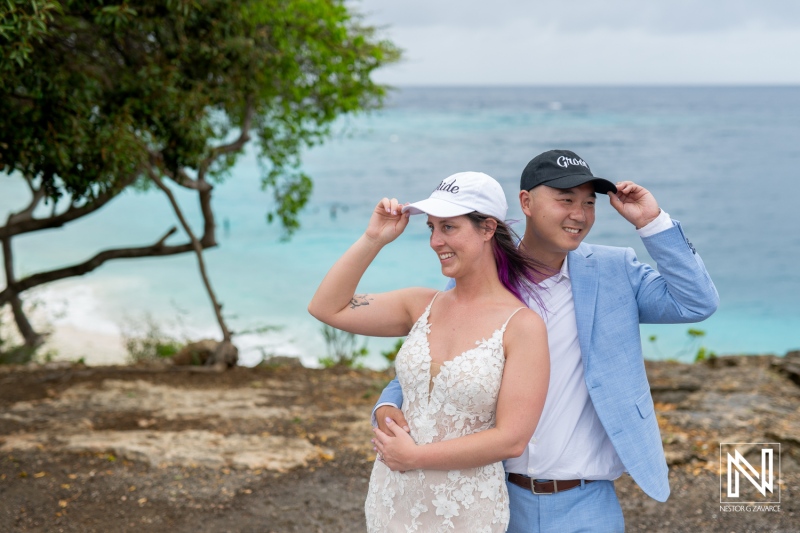 Couple enjoys a joyful trash the dress session in Curacao with stunning ocean backdrop and playful hats