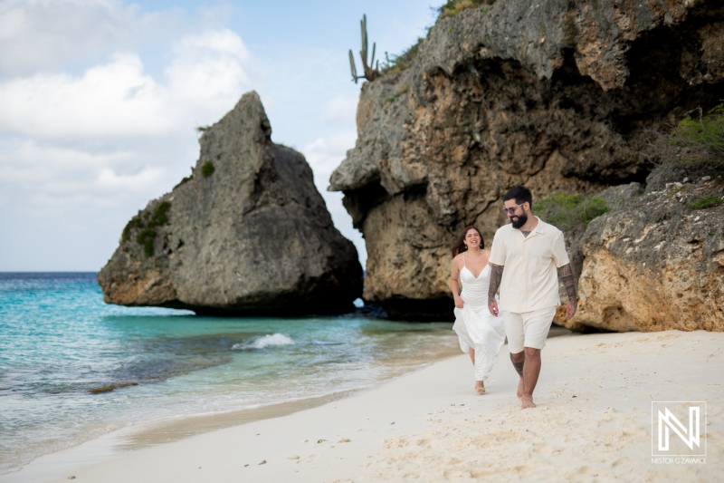 Couple enjoys a romantic walk at Cas Abao Beach in Curacao during a Trash the Dress session under a bright sky