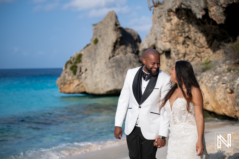 Couple enjoys trash the dress photoshoot at beach in Curacao near rock formations and clear water