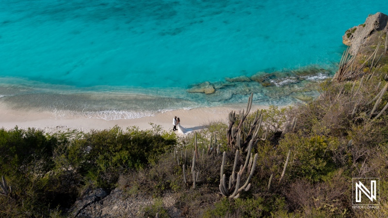 Couple participates in a trash the dress photoshoot at a beach in Curacao with clear blue water and sandy shore