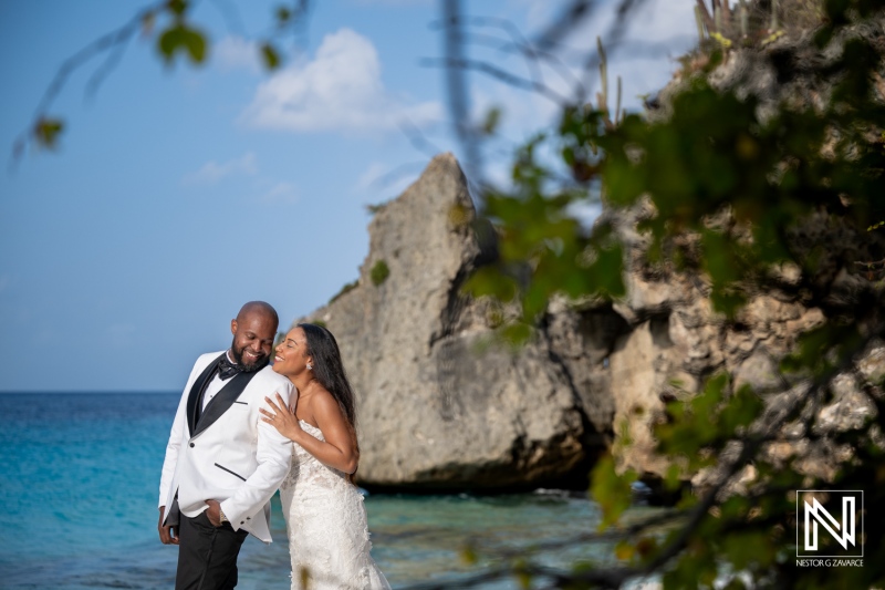 Couple enjoys trash the dress photoshoot in Curacao with rocks and sea in the background
