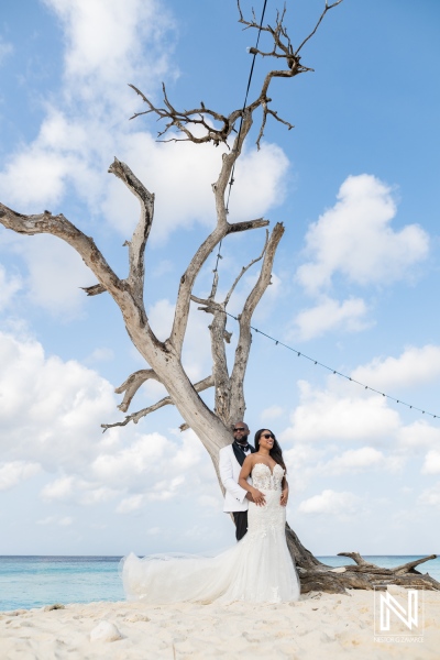 Couple enjoys trash the dress photoshoot on the beach in Curacao with a tree in the background