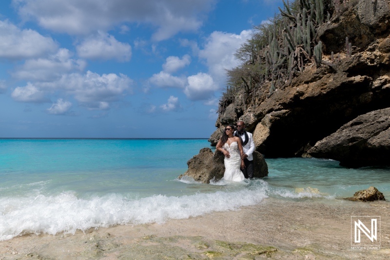 Couple enjoys a trash the dress photoshoot on the beach in Curacao with clear blue water and rocky background