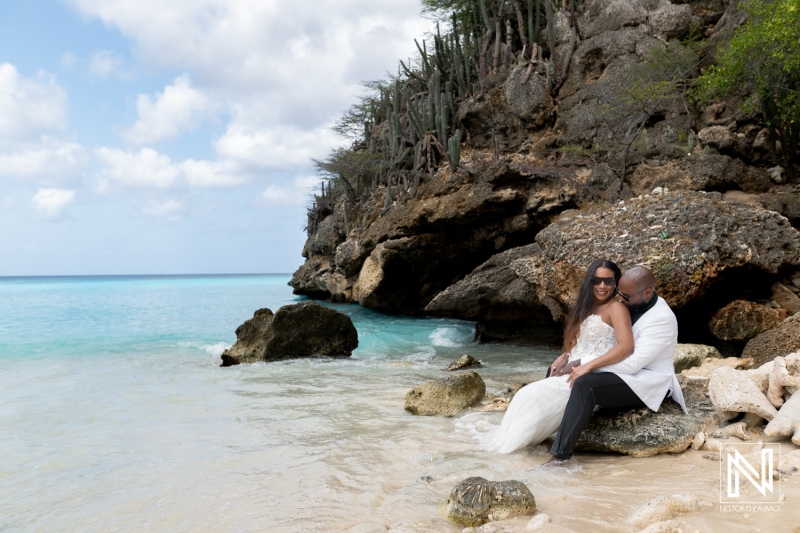 Trash the dress photoshoot in Curacao with couple sitting on rocks by the shore