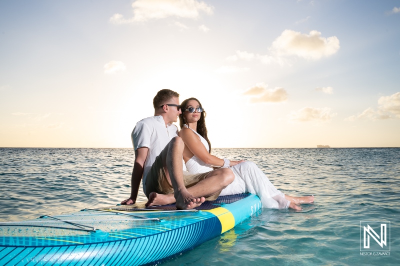 Couple enjoys trash the dress photoshoot at Cas Abao Beach during sunset in Curacao with stand up paddleboard