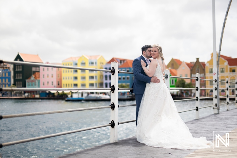 Couple enjoys romantic moment during trash the dress session in colorful Curacao harbor with historic buildings in background