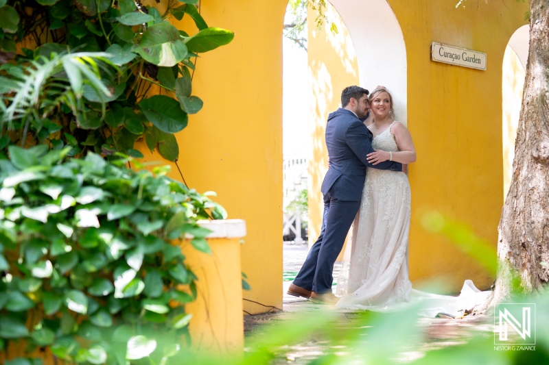 Couple shares a romantic moment at Curacao during Trash the Dress session with vibrant yellow backdrop