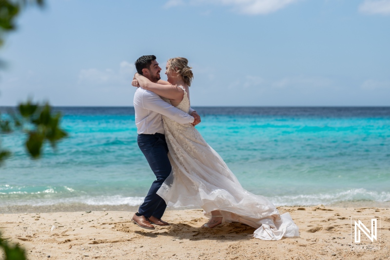 Couple joyfully dances on the beach during a Trash the Dress session in Curacao, capturing love in the tropical paradise with stunning turquoise waters