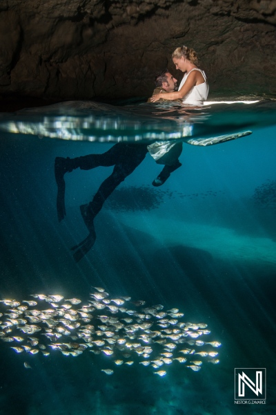 Underwater couple enjoying a moment in Curacao's clear waters while fish swim nearby