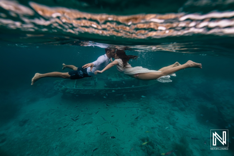 Underwater scene in Curacao shows two people swimming above a sunken ship with fish nearby
