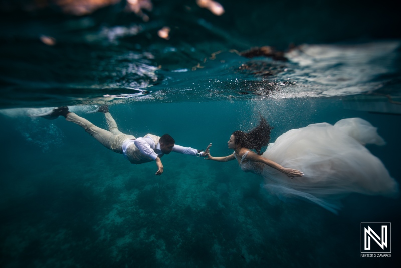 Couple swims underwater in Curacao during a wedding shoot in clear blue waters