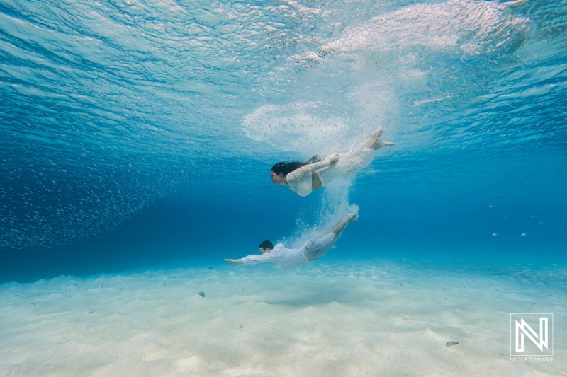 Swimming underwater in Curacao with two people moving in clear water