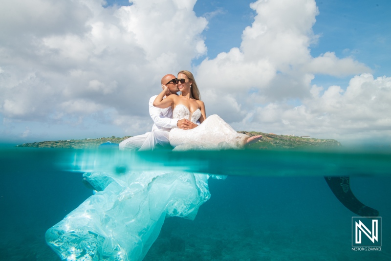 Couple enjoys time together in the water while their wedding attire floats around them in Curacao