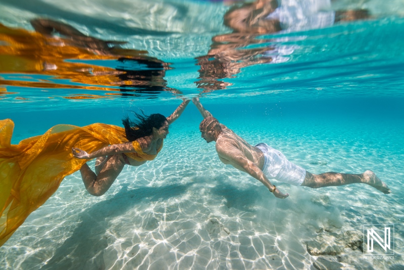 Swimmers explore the clear waters of Curacao while holding hands beneath the surface