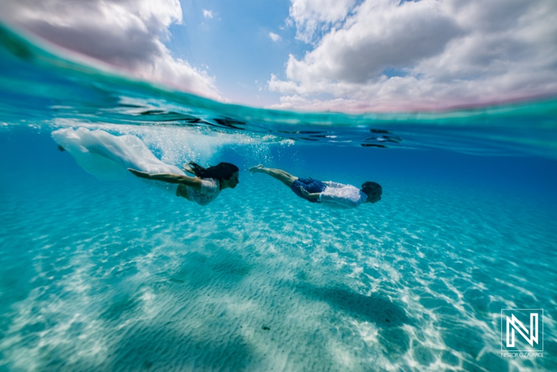 Underwater couple swims together in Curacao during a bright day near the ocean floor