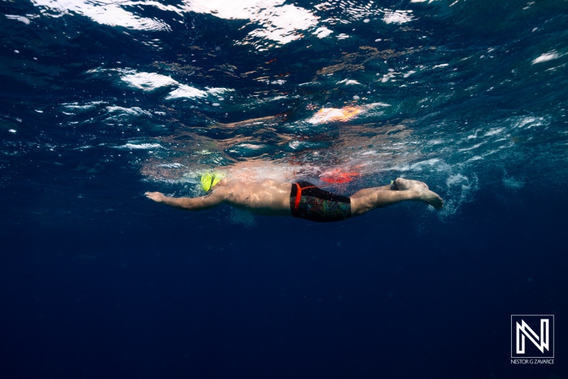 Underwater swimmer glides through the clear waters of Curacao during a bright sunny day